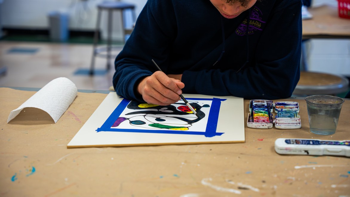 student using a brush and paint for an art project