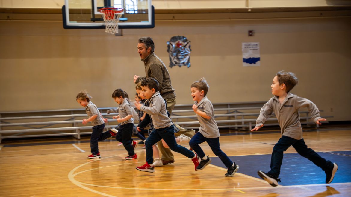 teacher and young students running in the gym